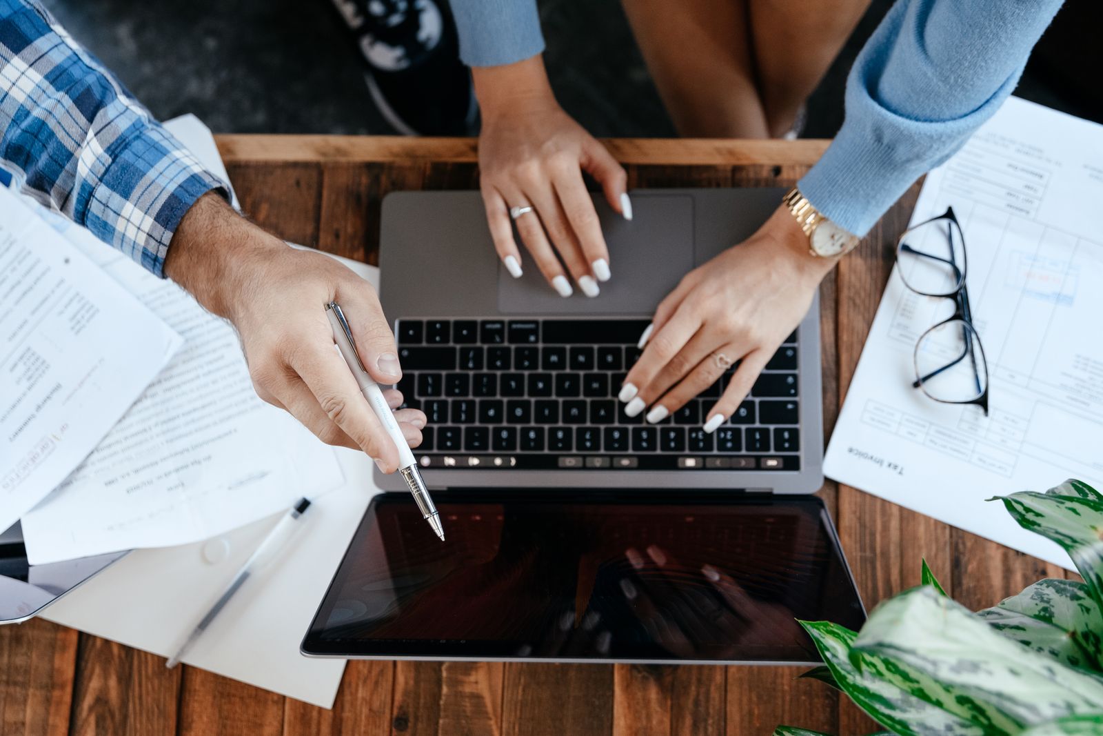 Hands collaborating around a laptop and business documents