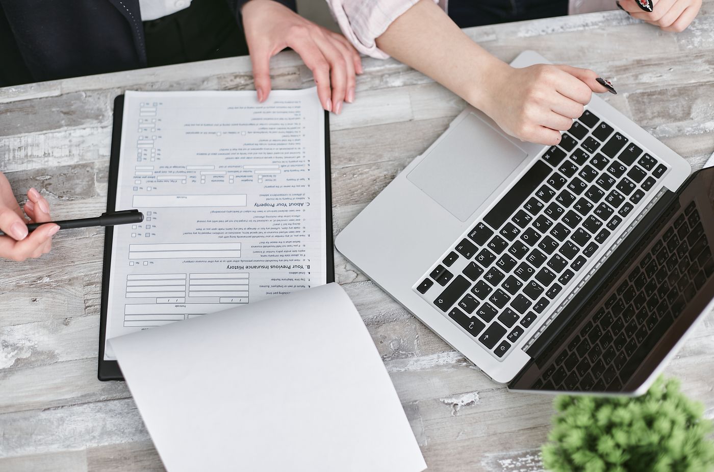 Hands reviewing documents beside a laptop
